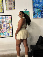 Load image into Gallery viewer, A woman wearing a beige halter style crop top and pleated skort set
